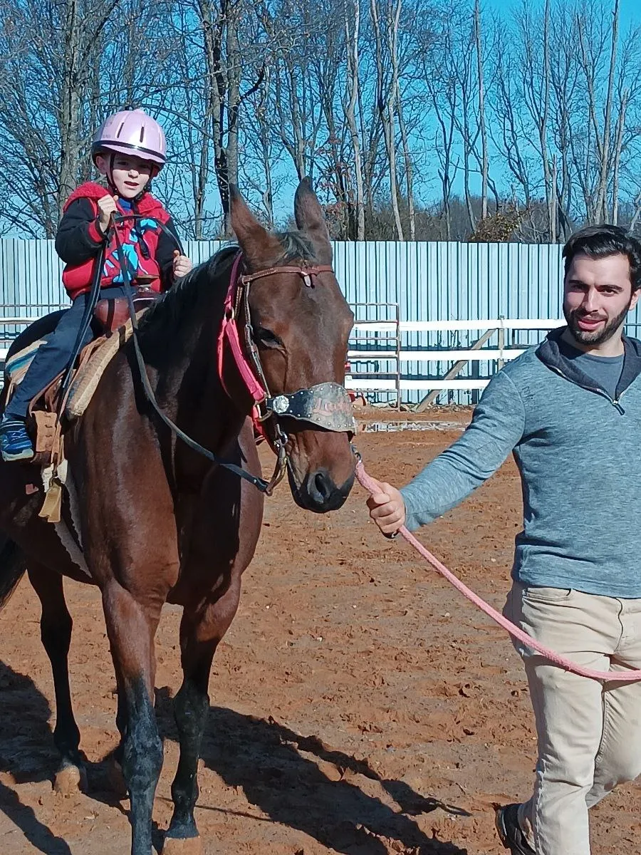 Evan giving pony ride to child